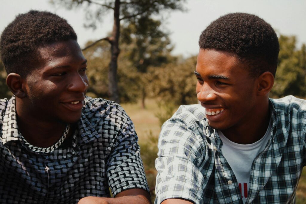 Two young men smiling and enjoying a sunny day outdoors, engaging in friendly conversation